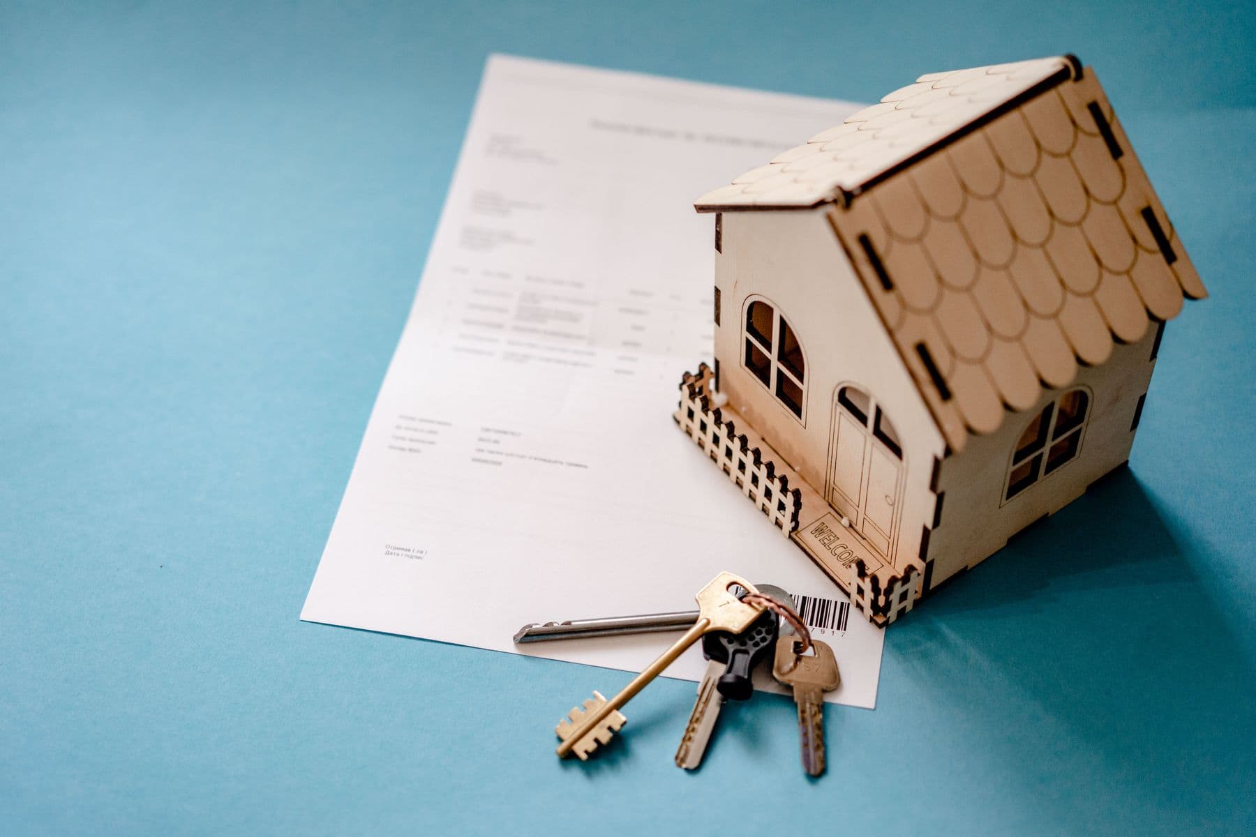 Wooden model house and keys resting on a document