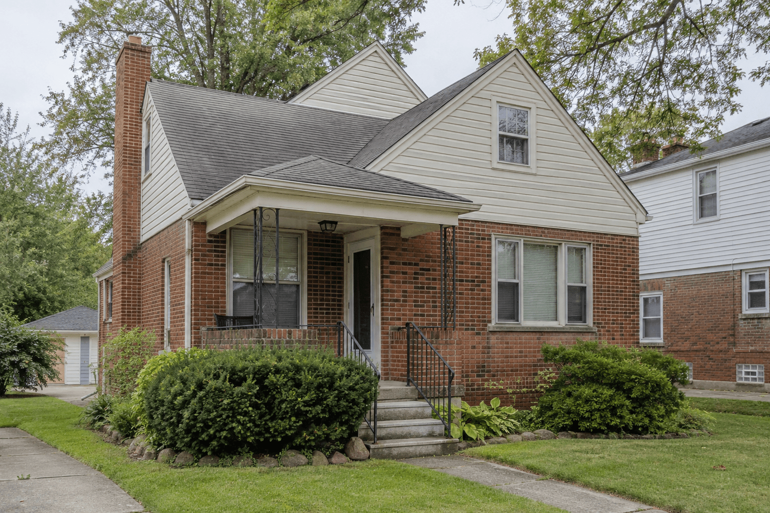A modest, well-kept but dated brick-and-siding home on a tree-lined Northeast Ohio residential street.
